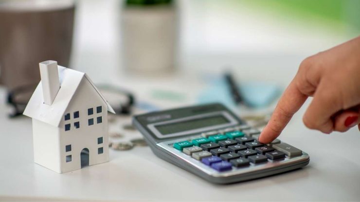 Женщина на калькуляторе считает выгоду от рефинансирования ипотеки
